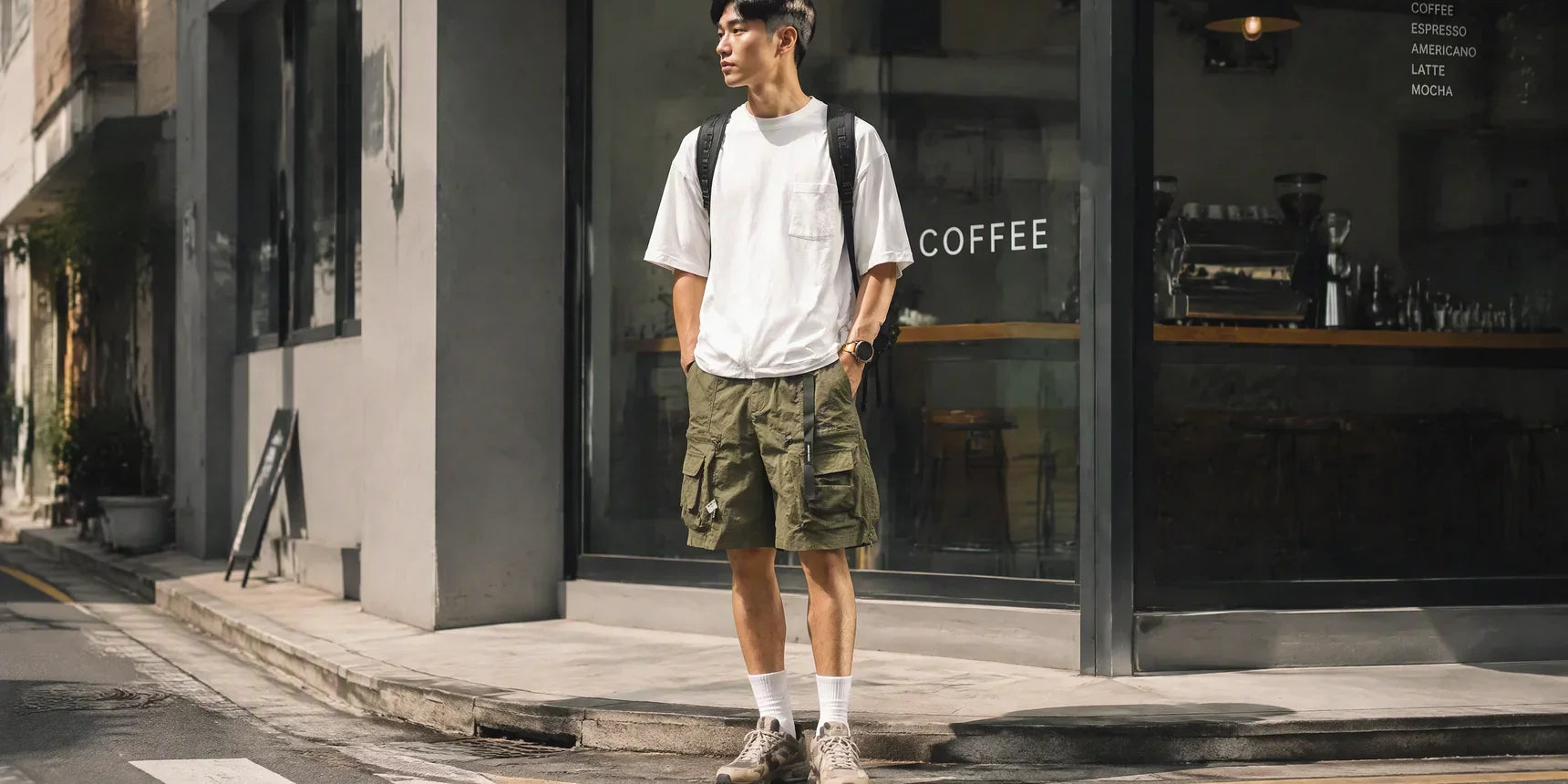 一位穿著時尚機能短褲的型男，在夏日城市街道中展現出舒適且俐落的穿搭風格。