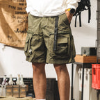 模特兒穿著莫尼綠機能工裝短褲，搭配白色防風外套，展現日系Cityboy寬鬆版型與膝上長度比例