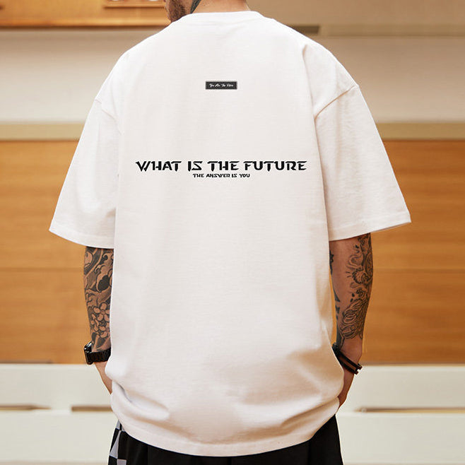 模特兒身穿白色寬鬆短袖T恤背面，展示黑色WHAT IS THE FUTURE英文標語印花與落肩版型細節