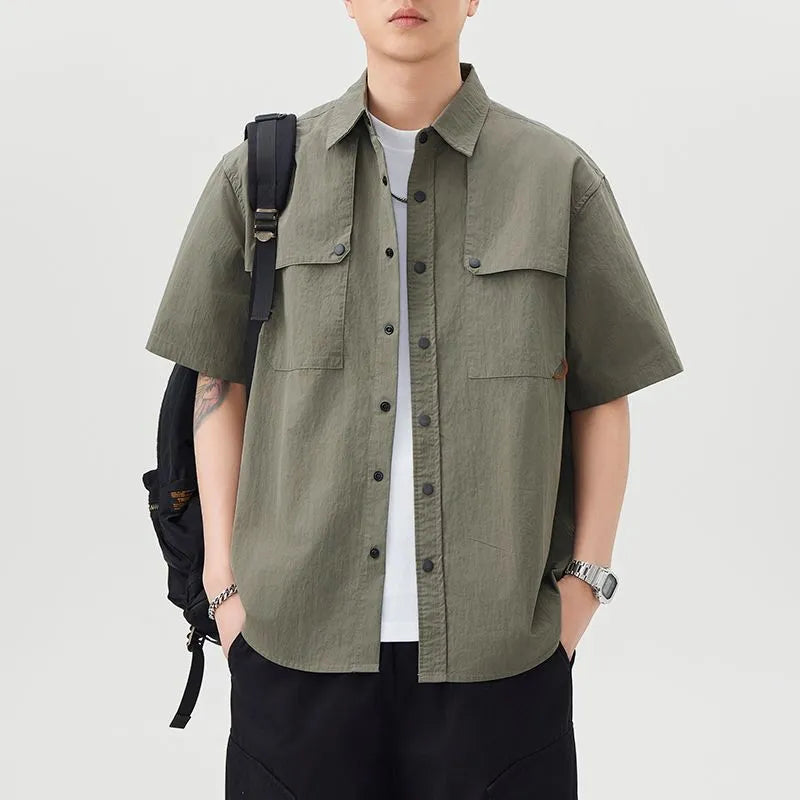 模特身穿軍綠色機能短袖襯衫，肩背黑色戶外背包，演繹日系山系穿搭與城市機能風。