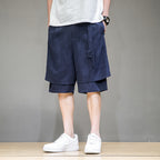 男模特示範 FLOW 系列深藍色棉麻五分褲，雙層下擺剪裁搭配白色板鞋，呈現 Clean Fit 街頭感。